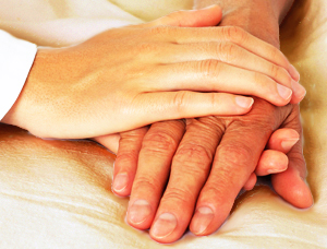 Woman Holding an Elderly Man's Hands in a Comforting Way